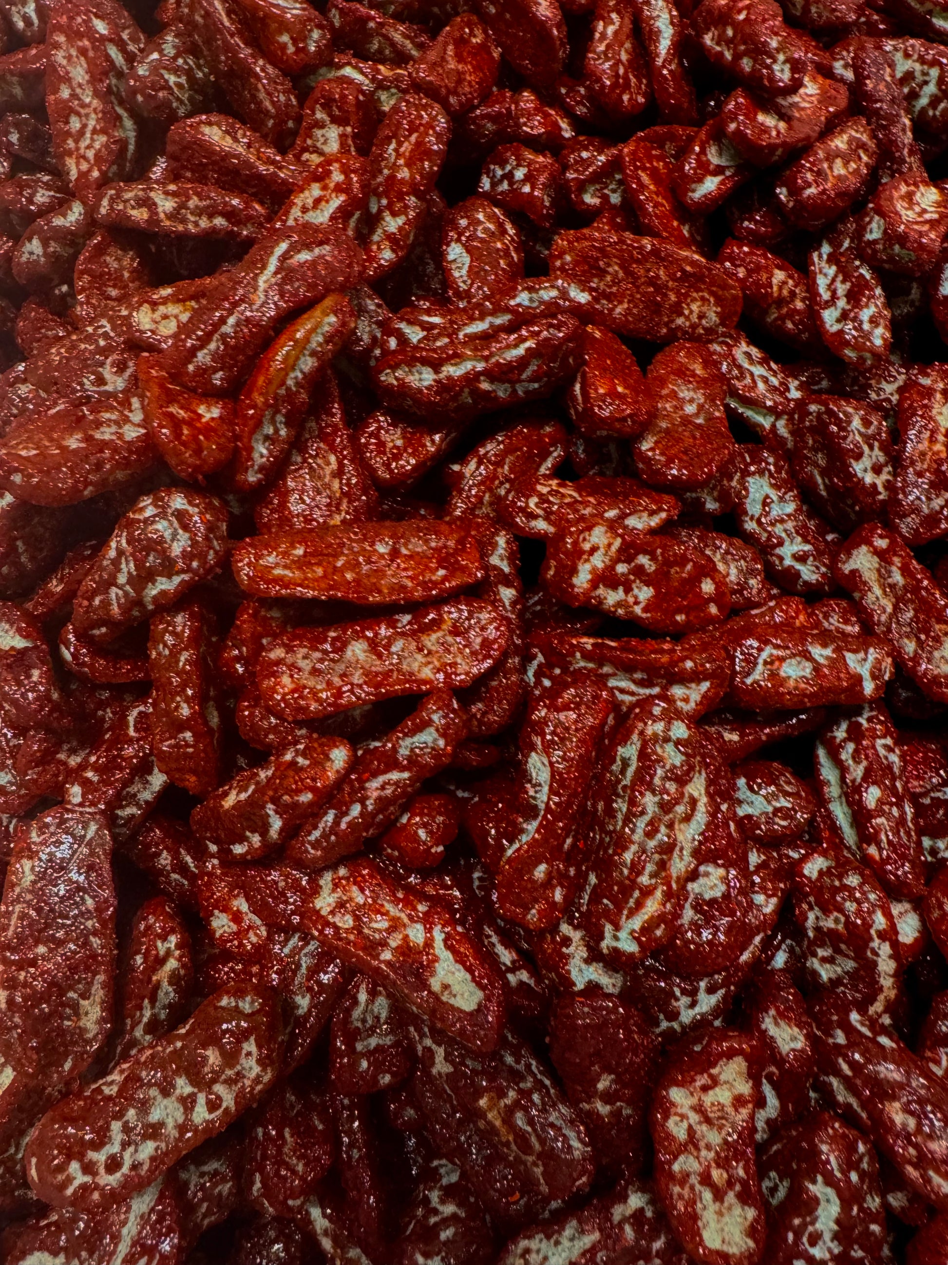 close up of gummies shape up as dill pickles covered in chamoy and chili 